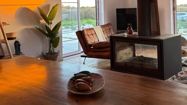 Una sala de estar acogedora con una mesa de madera, un sofá, una chimenea y un ventanal grande.