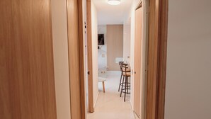 Ein Flur mit Holztüren, der zu einem Küchenbereich mit Esstisch und Stühlen führt.