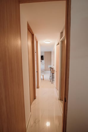 A hallway with wooden doors leading to a kitchen area with a dining table and chairs.
