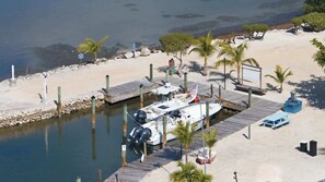 A marina with boats docked, a wooden pier, and a sandy beach with palm trees. - Tipsy Turtle -2 bed 3 bth Condo with Pool/ Dockage at Marina and gorgeous Gulf water views (Marathon)