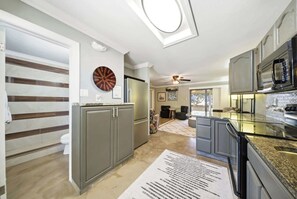 A modern kitchen with grey cabinets, a microwave, and a ceiling fan. - Tipsy Turtle -2 bed 3 bth Condo with Pool/ Dockage at Marina and gorgeous Gulf water views (Marathon)
