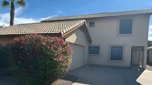 Ein Wohnhaus mit Ziegeldach, einem kleinen Vorgarten und einer Betonauffahrt.