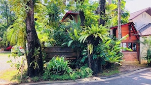 A lush garden with various tropical plants and a wooden signboard. - Room-204 Serene Teak Boutique Apartments (Chiang Mai)
