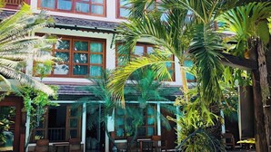 A two-story building with a swimming pool, surrounded by palm trees and outdoor seating. - Room-204 Serene Teak Boutique Apartments (Chiang Mai)