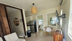 A modern living room with a sofa, chairs, a wooden coffee table, a TV, and a kitchen in the background. - Charming  Studio Apartment 1 in Fort Lauderdale.  (Fort Lauderdale)