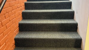 A staircase with carpeted steps, a metal handrail, and a brick wall. - 8031-Walk to Mayo - Cozy 2 bed/ 1 Bath unit with free parking (Rochester)