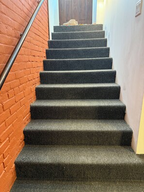 A staircase with carpeted steps, a metal handrail, and a brick wall. - 8031-Walk to Mayo - Cozy 2 bed/ 1 Bath unit with free parking (Rochester)