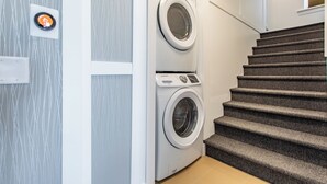A laundry area with two washing machines, a thermostat, and a staircase. - 8031-Walk to Mayo - Cozy 2 bed/ 1 Bath unit with free parking (Rochester)