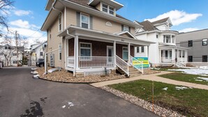 A two-story house with a front porch, a small front yard, and a driveway. - 8031-Walk to Mayo - Cozy 2 bed/ 1 Bath unit with free parking (Rochester)