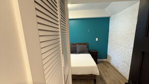 A bedroom with a bed, a nightstand, a wall with a textured pattern, and a door. - 8031-Walk to Mayo - Cozy 2 bed/ 1 Bath unit with free parking (Rochester)