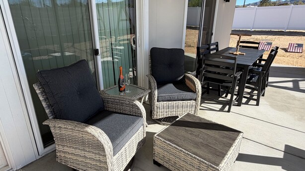 A patio with wicker furniture, including chairs and a table, and a bottle of champagne. - 2-bedroom house in charming Joshua Tree with pool (Joshua Tree)