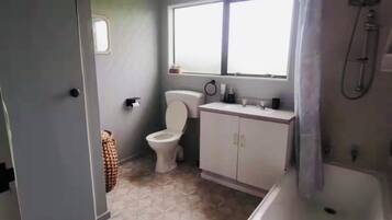 Baño con inodoro, lavabo, ducha y ventana.