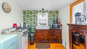 Una cocina compacta con estufa, microondas, fregadero y armarios de madera.