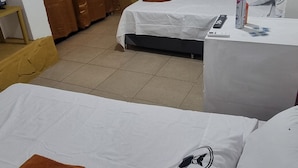 Ein Hotelzimmer mit zwei Betten, einem Schrank, einem Nachttisch mit einer Flasche und einer Wandleuchte.