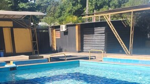Ein Schwimmbecken mit klarem, blauem Wasser, umgeben von einer Holzterrasse und einem Metallgeländer.