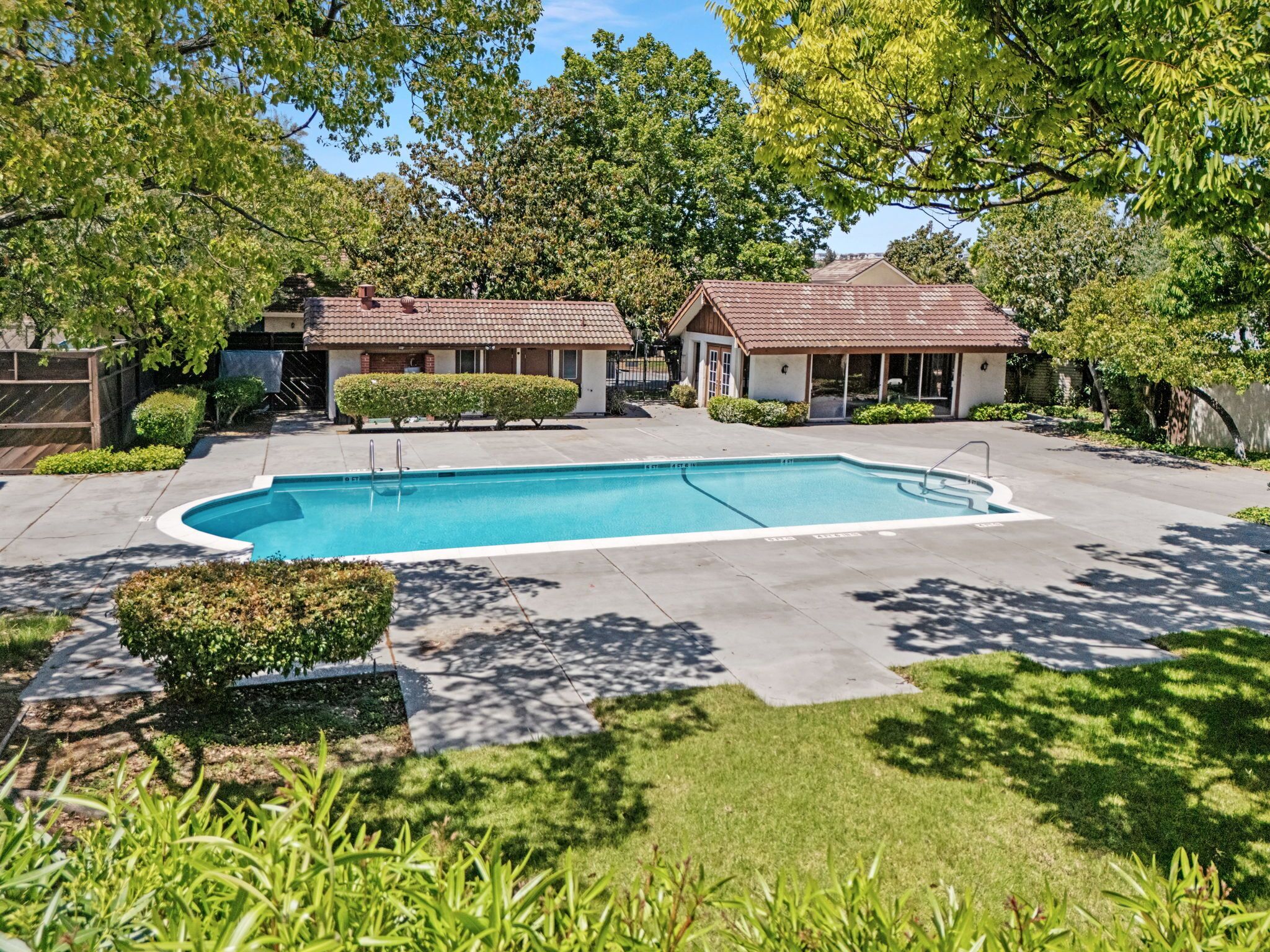 Une propriété résidentielle dotée d  ’une piscine, de deux maisons et d’une pelouse bien entretenue.