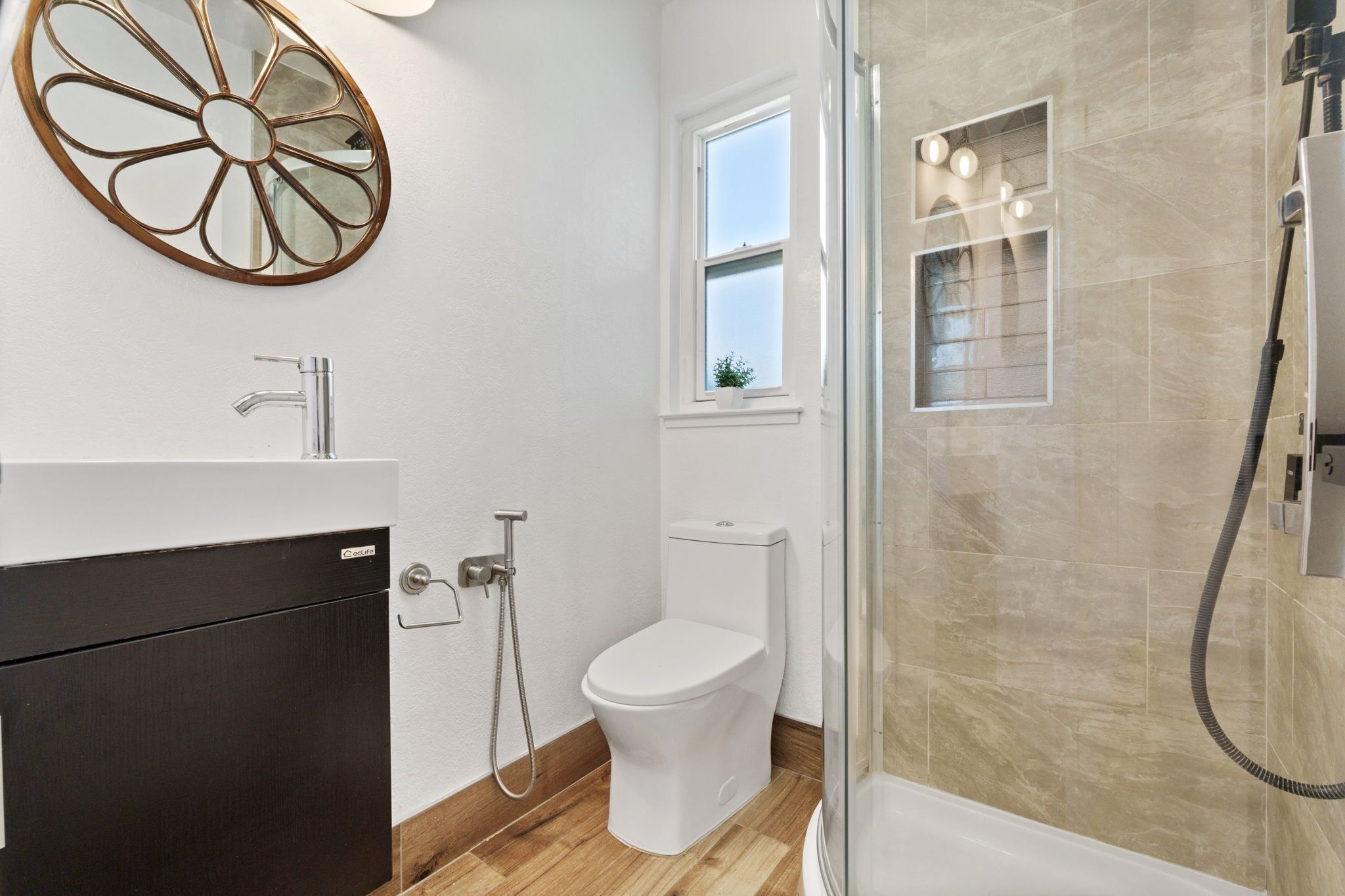 A bathroom with a toilet, a shower, a sink, and a window.