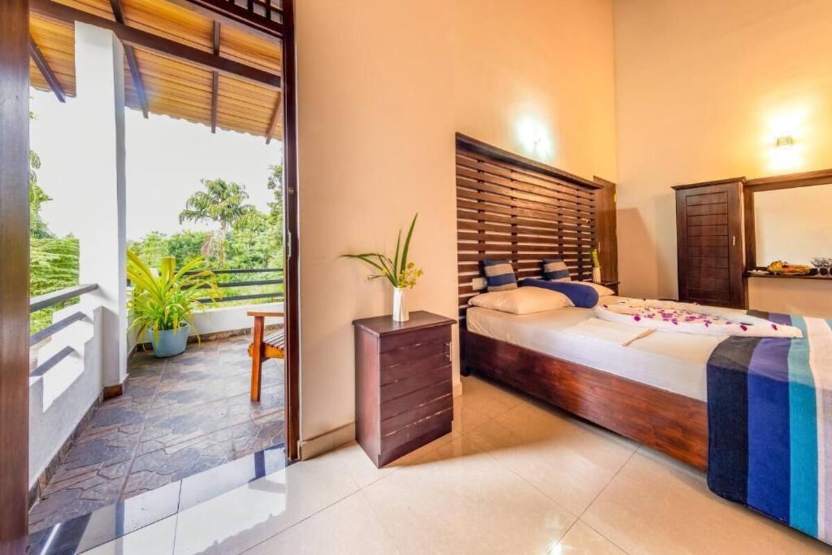 Une chambre à coucher avec un lit, une commode, une table de chevet et une plante en pot.