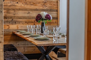 Ein Holztisch gedeckt mit Tellern, Gläsern und einer Blumenvase.