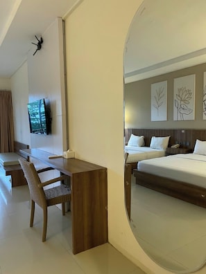 Una camera d'albergo con un letto, una scrivania, una sedia, una televisione e opere d'arte appese al muro.