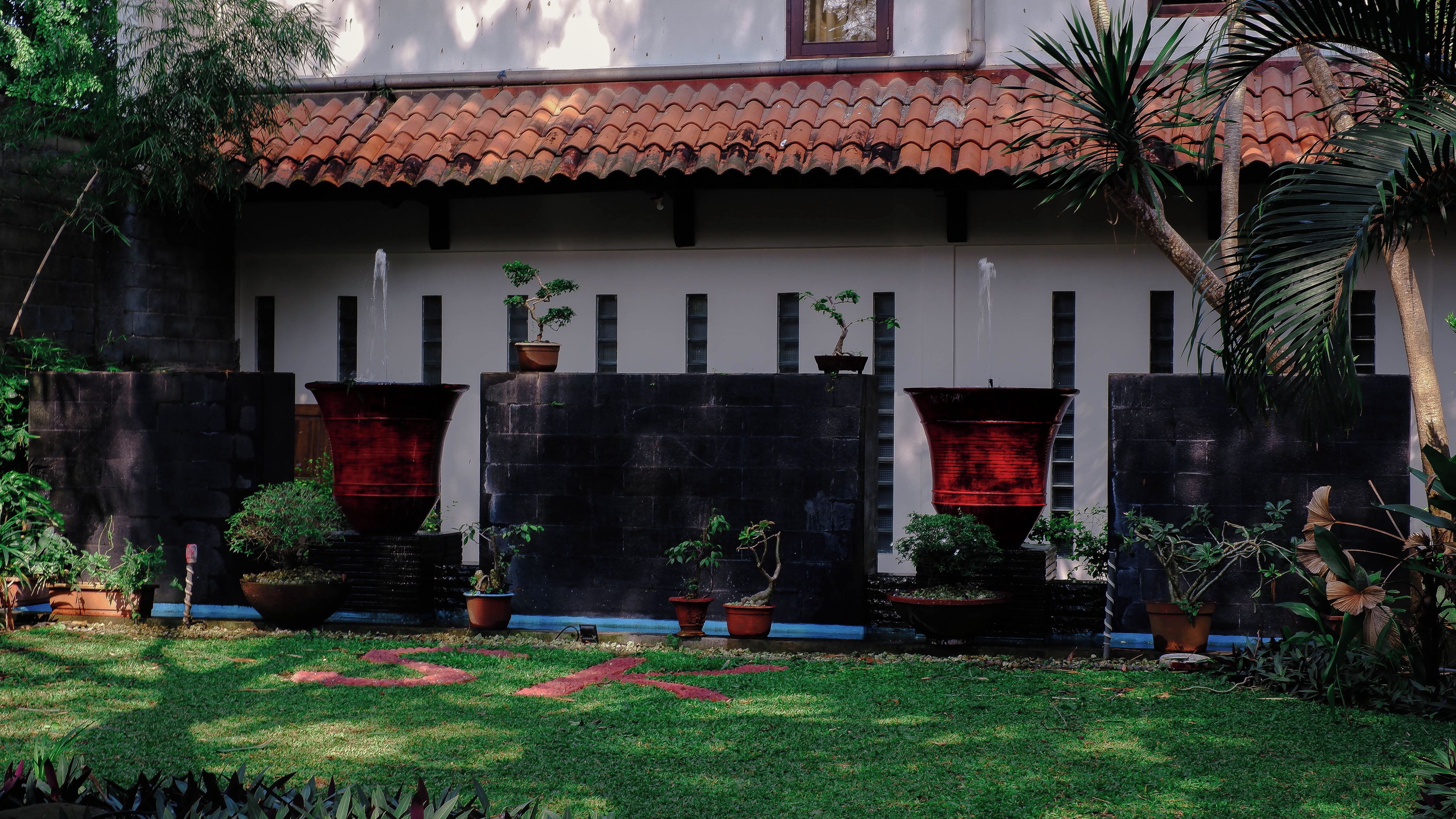 Un edificio con tejado de baldosas, pared de piedra y plantas en macetas.