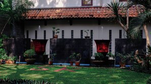 A building with a tiled roof, a stone wall, and potted plants. - Surya Kencana Seaside Hotel Pangandaran (Pangandaran)