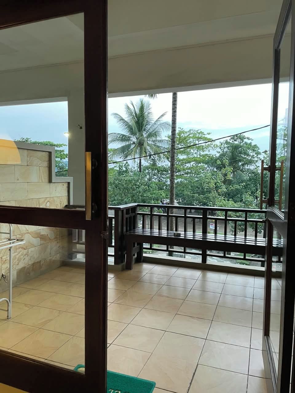 A balcony with a view of a lush green landscape and palm trees.