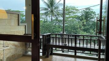 A balcony with a view of a lush green landscape and palm trees.