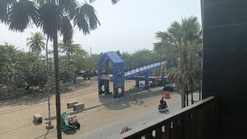 Vista desde un balcón sobre una calle con un puente peatonal azul, palmeras y una motocicleta.