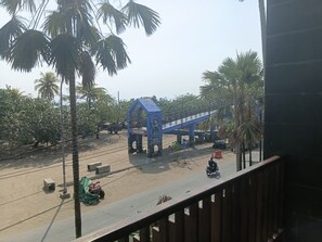Vista da un balcone su una strada con un ponte pedonale blu, palme e uno scooter.
