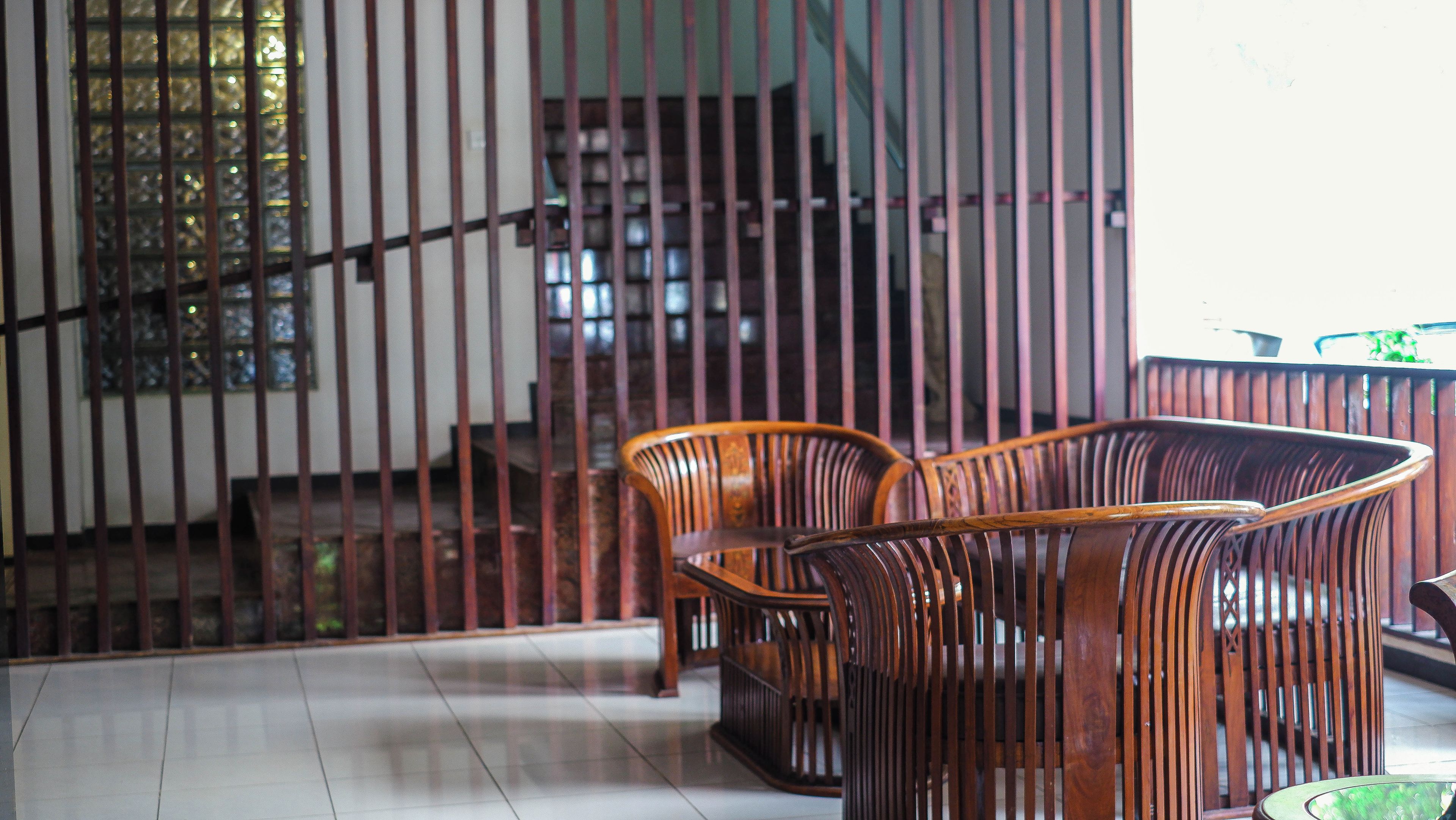 Una escalera con barandillas de madera, suelo de baldosas y dos sillas de madera.