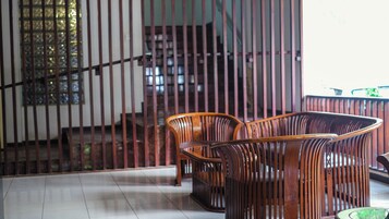 Una escalera con barandillas de madera, suelo de baldosas y dos sillas de madera.
