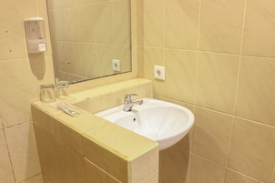 Un baño con un lavamanos blanco, un espejo y un dispensador de jabón en la pared.