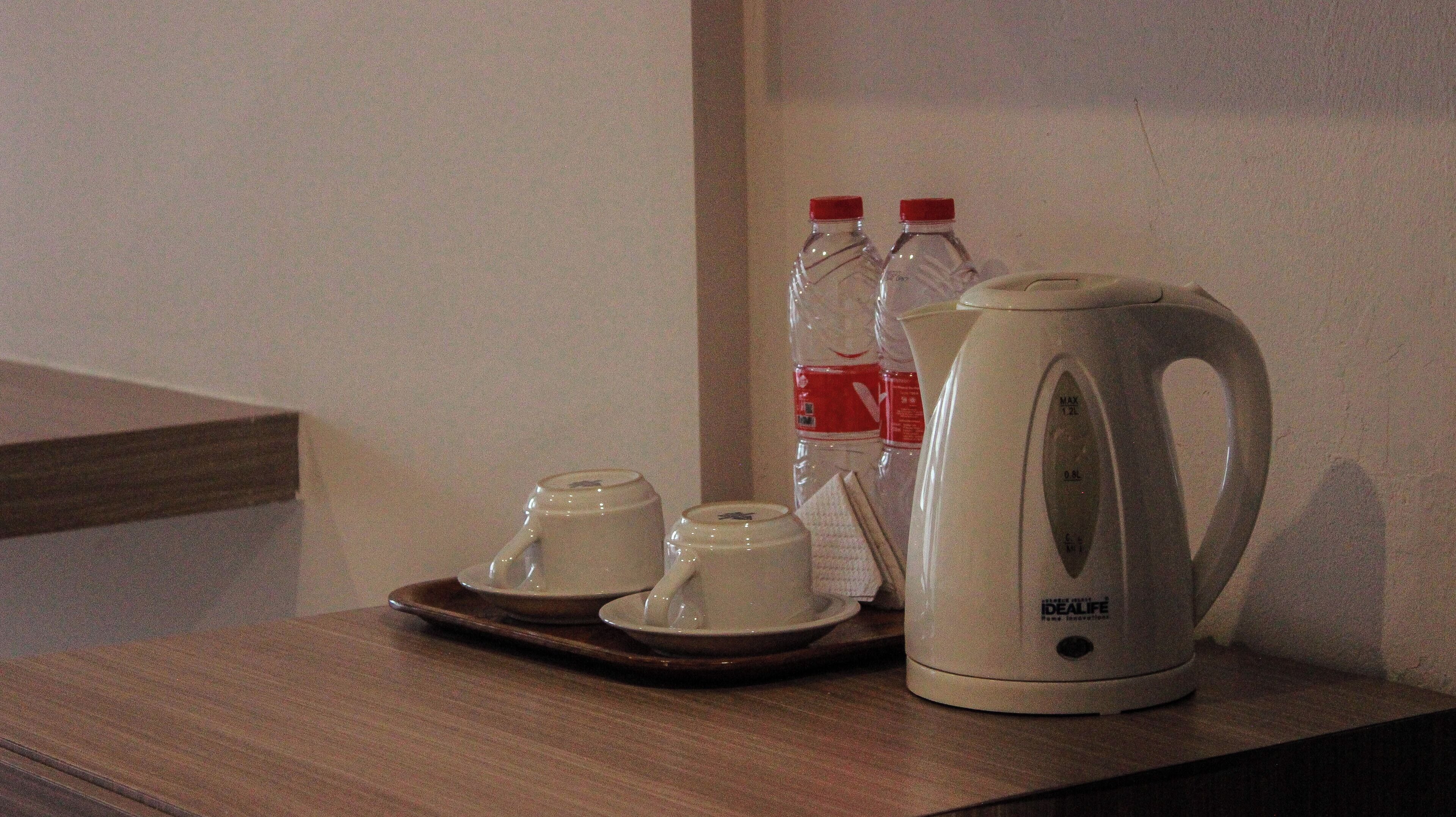 Una encimera de cocina con una tetera, dos tazas y dos botellas de agua.