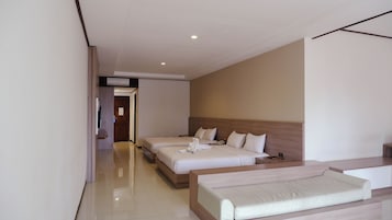A hotel room with two beds, a sofa, a flat-screen TV, and a wooden headboard.