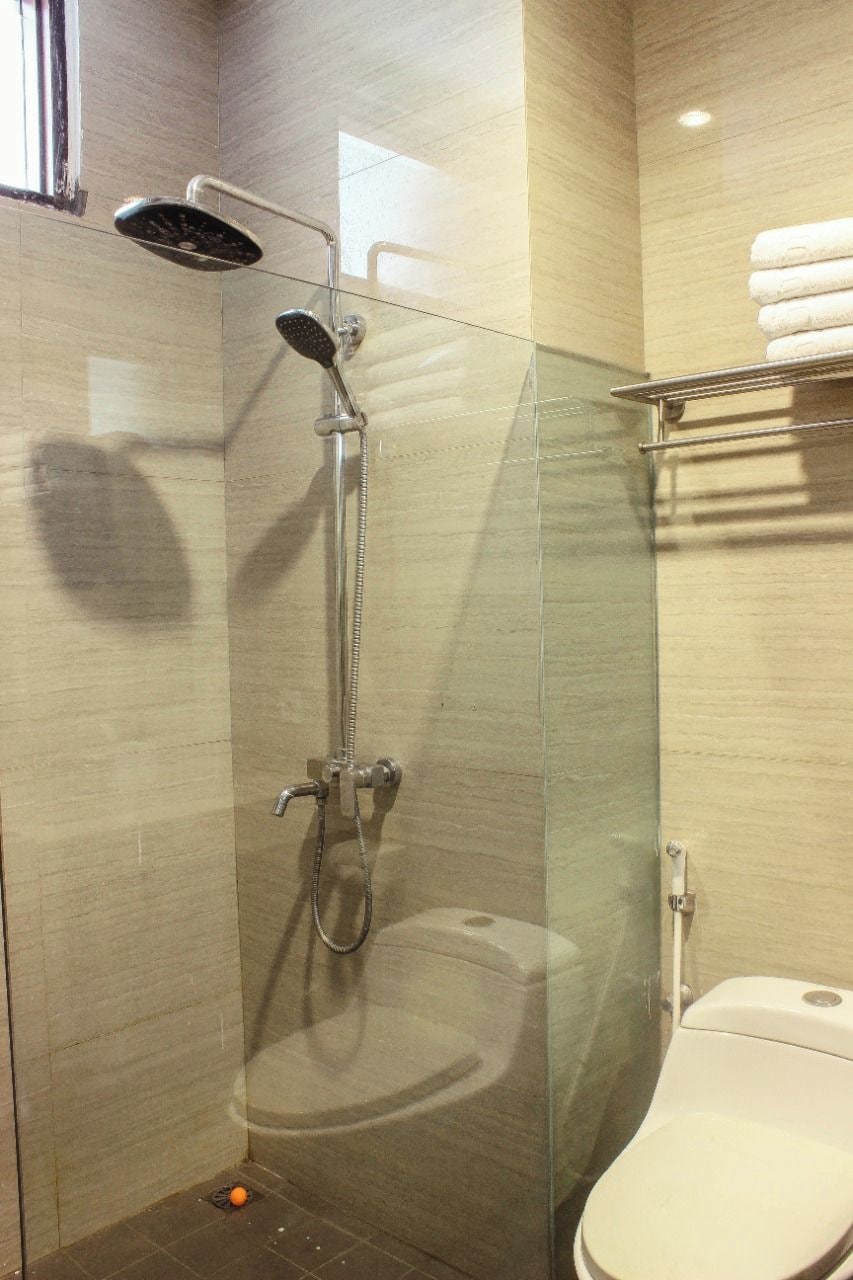A glass-enclosed shower stall with a handheld showerhead and a handheld shower head.