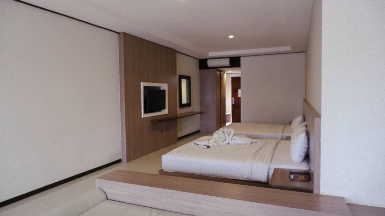 Une chambre d’hôtel avec un lit, une télévision et un petit coin salon.