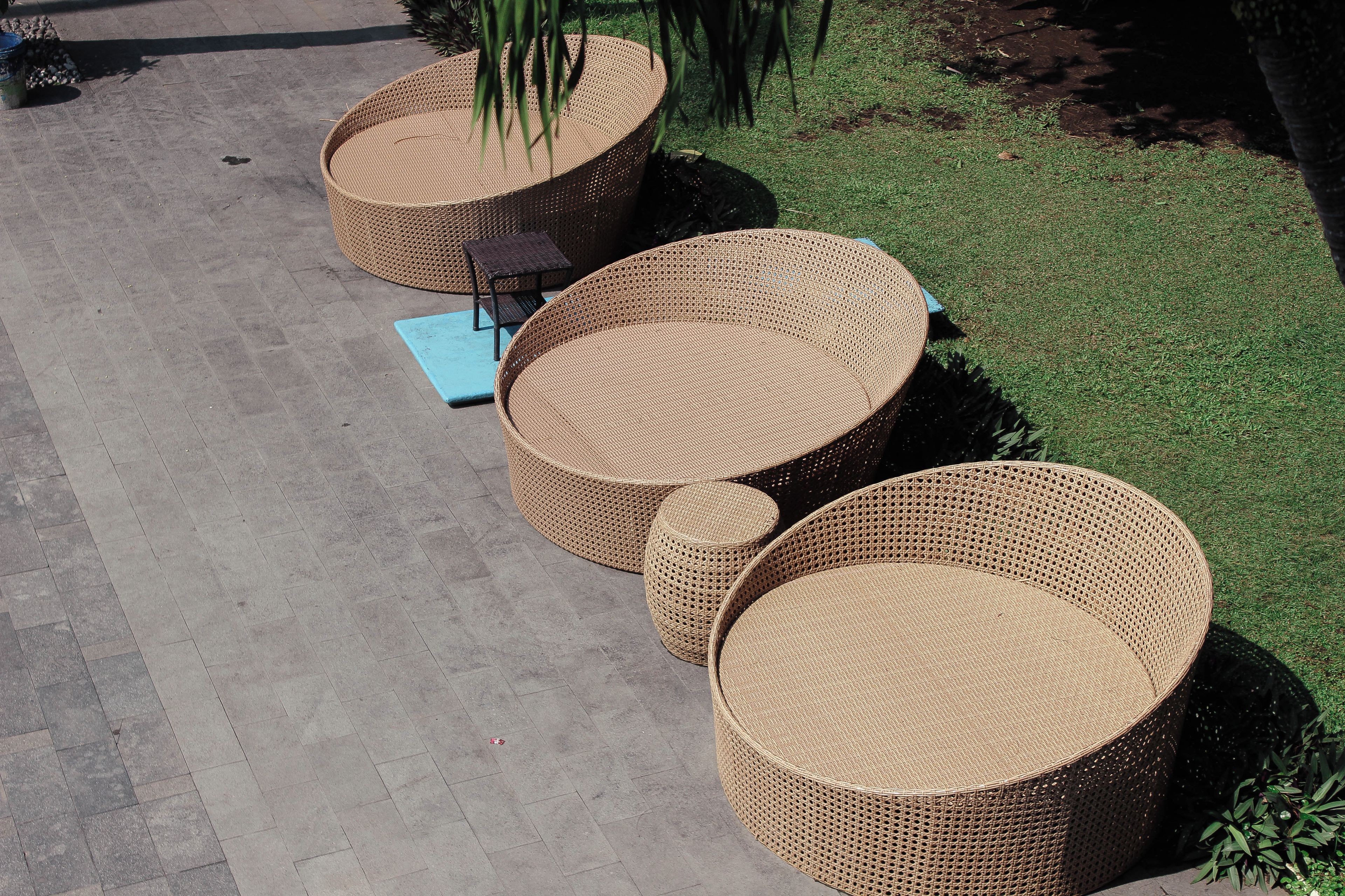 Outdoor wicker furniture arranged on a paved area with a grassy background.