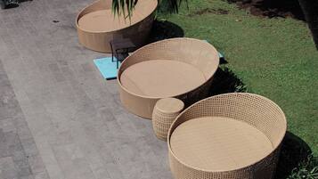 Outdoor wicker furniture arranged on a paved area with a grassy background.