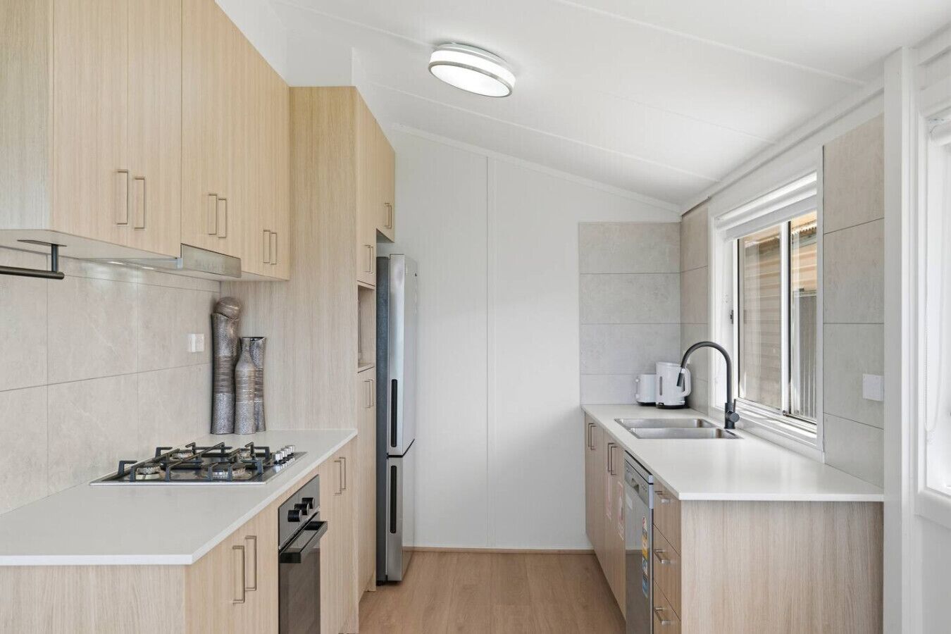 A compact kitchen with a gas stove, stainless steel refrigerator, and a dishwasher.