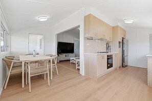 A modern kitchen with light wood cabinets, a built-in oven, and a refrigerator.