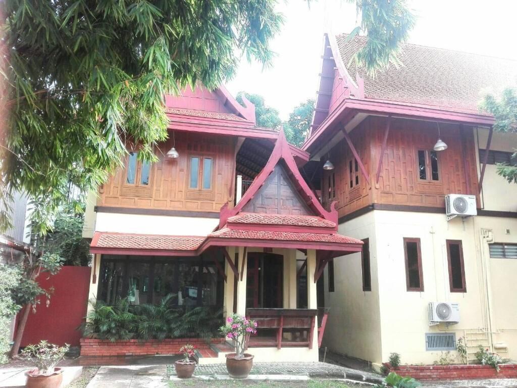 A traditional wooden house with a red roof, large windows, and a porch.