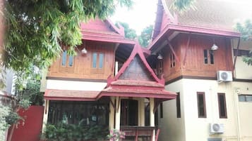 A traditional wooden house with a red roof, large windows, and a porch.