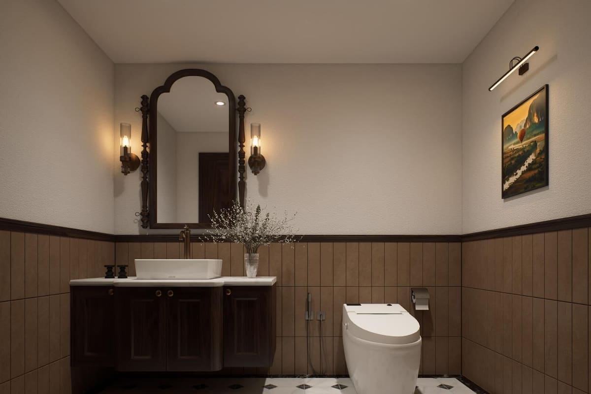 Une salle de bain avec un lavabo blanc, des meubles en bois foncé, des toilettes blanches, un miroir avec des appliques murales et un tableau accroché au mur.