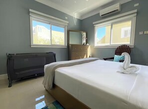 Ein Schlafzimmer mit Bett, Schminktisch, Heizkörper und zwei Fenstern mit Blick.