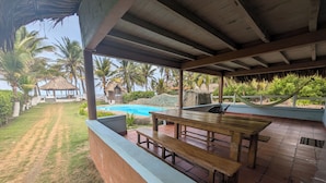 Ein überdachter Außenbereich mit Pool, Holztisch und Bänken.