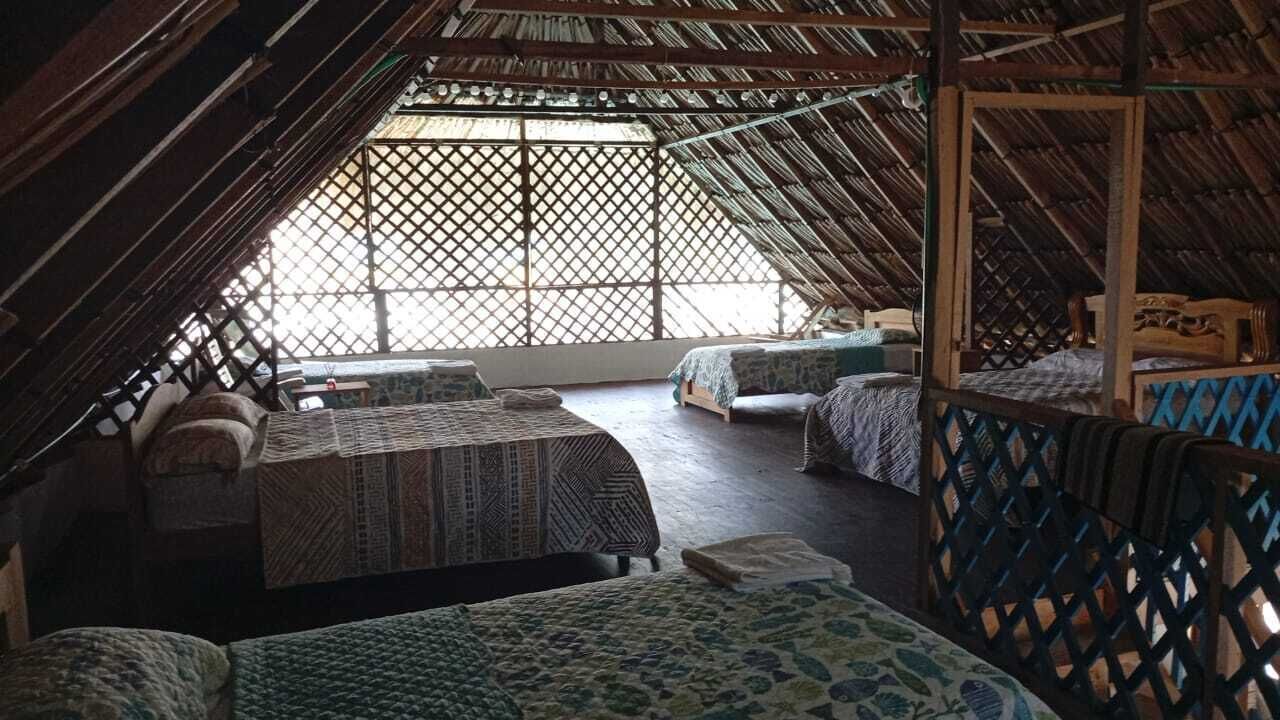 Une pièce avec un plafond en pente, des lits en bois avec une literie à motifs et une fenêtre à croisillons.