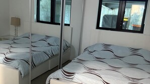 Een slaapkamer met twee bedden, een spiegel en een raam.