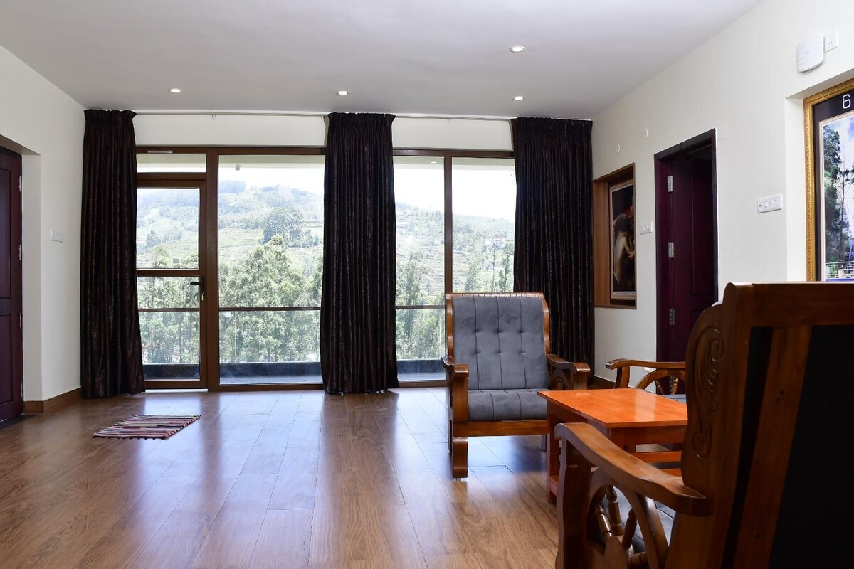 A spacious room with a large window, a wooden chair, a wooden table, and a door.