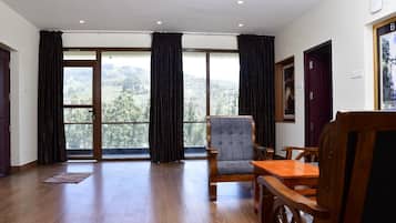 A spacious room with a large window, a wooden chair, a wooden table, and a door.